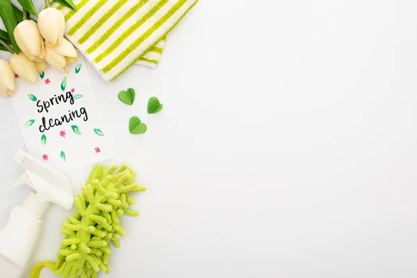 Top view of spring tulips and green cleaning supplies near spring cleaning card on white background — Stock Photo