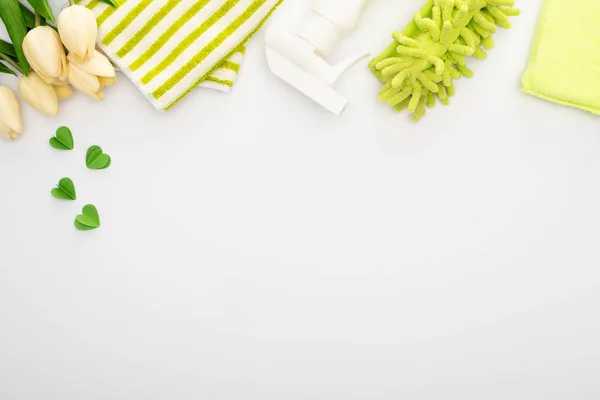 Top view of spring tulips and green cleaning supplies on white background — Stock Photo