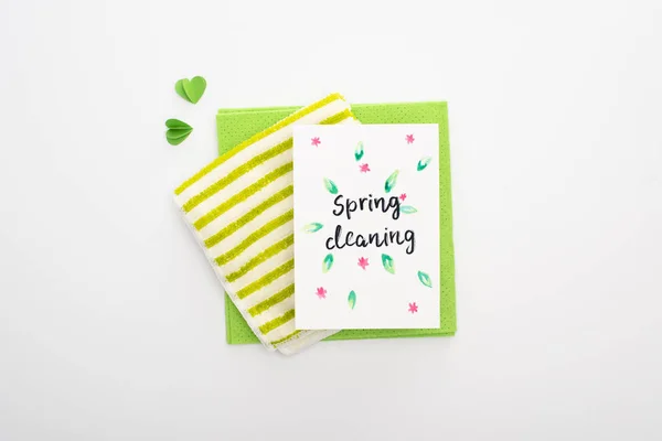 Vista superior de la tarjeta de limpieza de primavera, trapos y corazones sobre fondo blanco - foto de stock