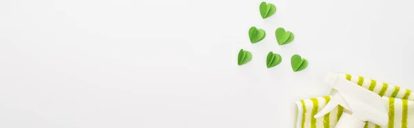 Top view of cleaning supplies and green hearts on white background, panoramic shot — Stock Photo