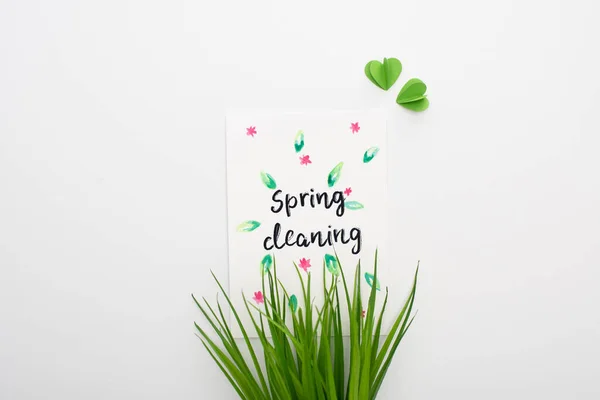 Top view of green grass and spring cleaning card on white background — Stock Photo