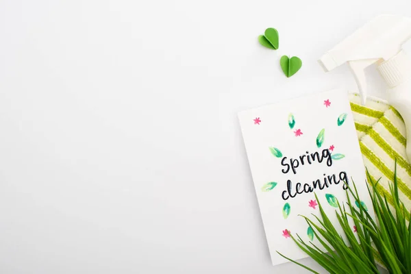 Top view of green grass and cleaning supplies near spring cleaning card on white background — Stock Photo
