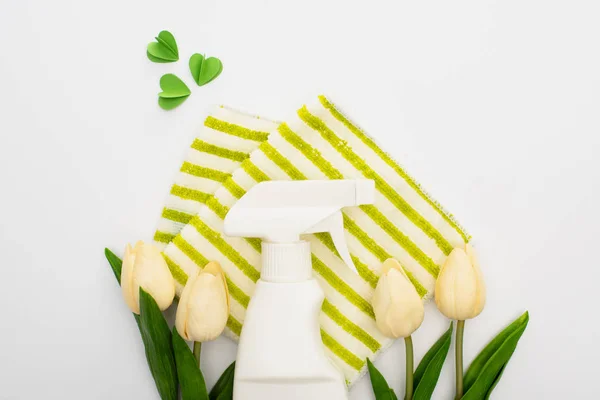 Top view of spring tulips and green cleaning supplies with hearts on white background — Stock Photo