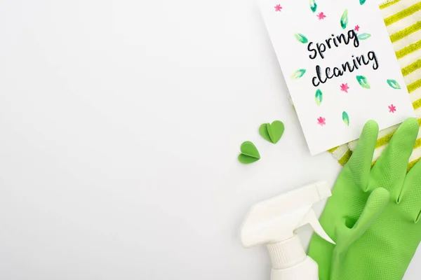 Vue du dessus des fournitures de nettoyage vert avec des coeurs près de la carte de nettoyage de printemps sur fond blanc — Photo de stock