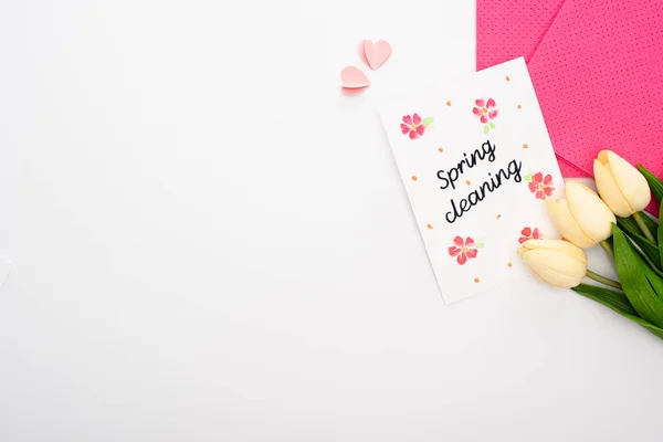 Вид зверху на тюльпани і рожеві ганчірки біля весняної картки для прибирання на білому тлі — стокове фото