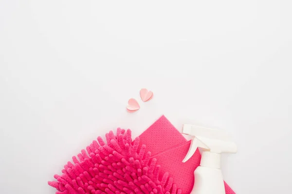 Vista superior de los suministros de limpieza de color rosa y corazones sobre fondo blanco - foto de stock
