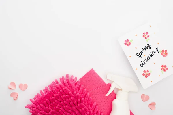 Top view of pink cleaning supplies and hearts near spring cleaning card on white background — Stock Photo