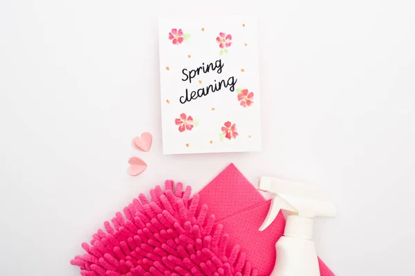 Top view of pink cleaning supplies and hearts near spring cleaning card on white background — Stock Photo