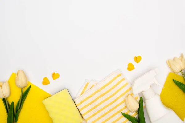 Top view of spring tulips and yellow cleaning supplies with hearts on white background — Stock Photo