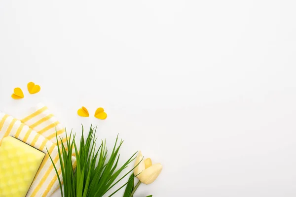 Вид зверху весняних тюльпанів і зеленої трави біля жовтих приладів для прибирання на білому тлі — стокове фото