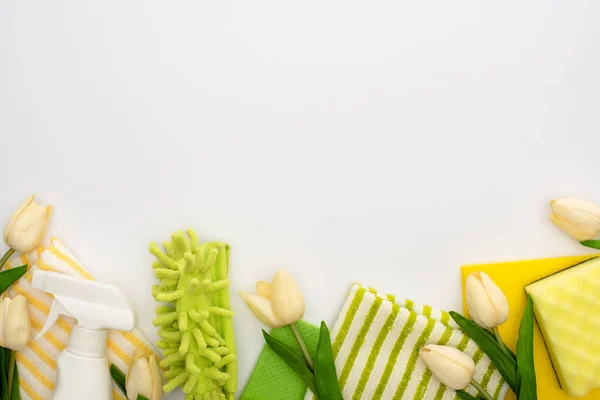 Vue de dessus des tulipes de printemps, fournitures de nettoyage vert et jaune sur fond blanc — Photo de stock