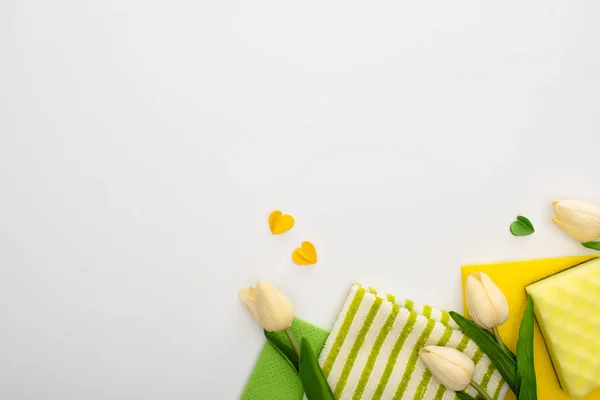 Vue de dessus des tulipes de printemps, fournitures de nettoyage vert et jaune avec des coeurs sur fond blanc — Photo de stock