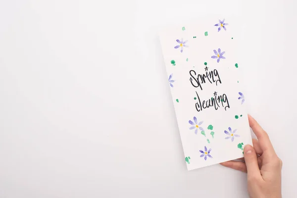 Vista cortada da mulher segurando cartão de limpeza primavera no fundo branco — Fotografia de Stock