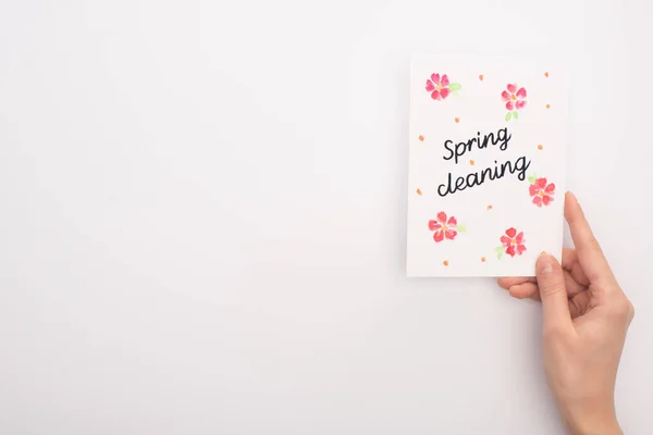 Vista recortada de la mujer sosteniendo la tarjeta de limpieza de primavera sobre fondo blanco - foto de stock