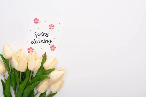 Вид зверху весняних тюльпанів біля весняної картки для прибирання на білому тлі — стокове фото