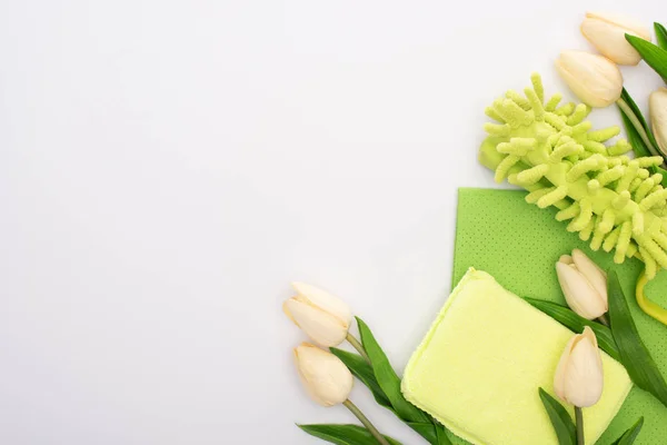 Vista dall'alto di tulipani primaverili e forniture per la pulizia verde su sfondo bianco — Foto stock