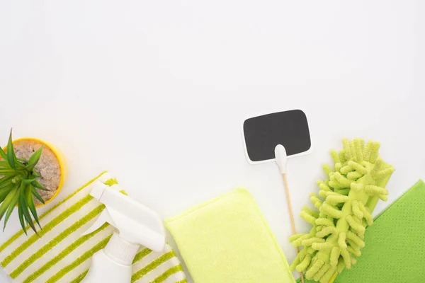 Top view of houseplant and green cleaning supplies with blank card on white background — Stock Photo