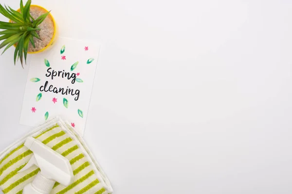 Top view of houseplant and cleaning supplies near spring cleaning card on white background — Stock Photo