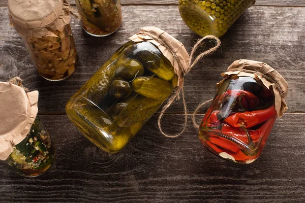 Top view of homemade tasty pickles in jars on wooden table — Stock Photo