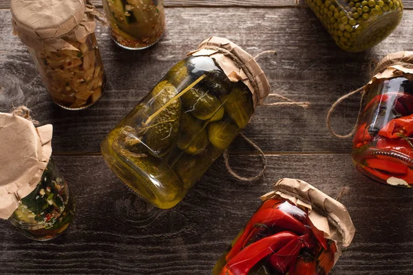 Top view of homemade tasty pickles in jars on wooden table — Stock Photo