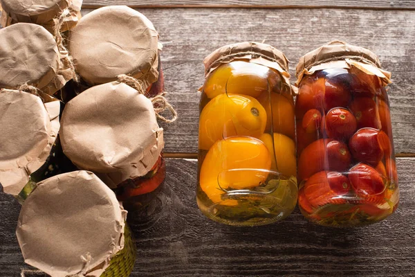 Blick von oben auf hausgemachte leckere Dosen rote und gelbe Tomaten in der Nähe von Gläsern auf dem Holztisch — Stockfoto