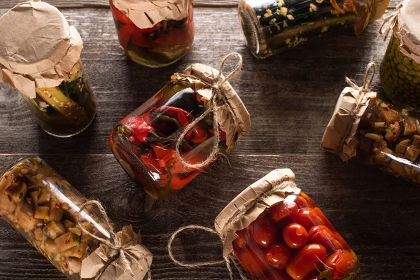 Top view of homemade tasty pickles in jars on wooden table — Stock Photo