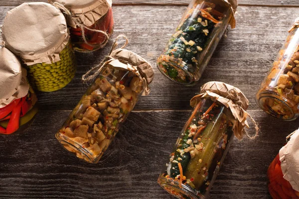 Blick von oben auf hausgemachte leckere Essiggurken in Gläsern auf Holztisch — Stockfoto