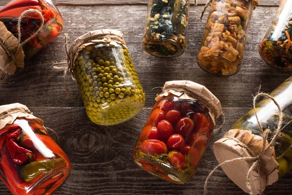 Top view of homemade tasty pickles in jars on wooden table — Stock Photo