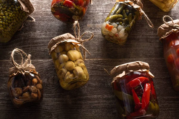 Top view of homemade delicious pickles in jars on wooden table — Stock Photo