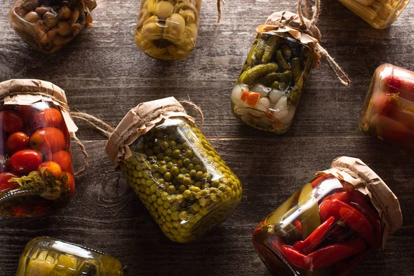 Top view of homemade delicious pickles in jars on wooden table — Stock Photo