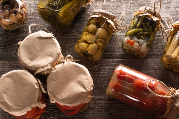 Top view of homemade delicious pickles in jars on wooden table — Stock Photo