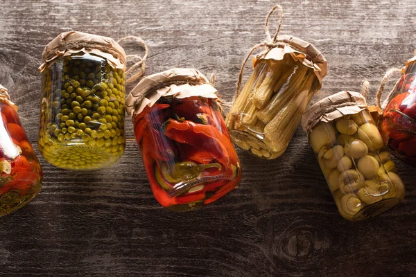 Top view of homemade tasty pickles in jars on wooden table — Stock Photo