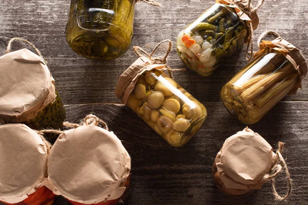 Top view of homemade delicious pickles in jars on wooden table — Stock Photo