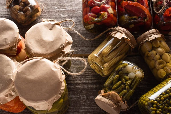 Top view of delicious pickles in jars on wooden table — Stock Photo