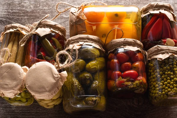 Top view of delicious pickles in jars on wooden table — Stock Photo