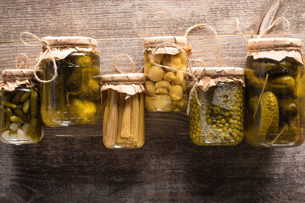 Top view of green tasty homemade pickles in jars on wooden rustic table — Stock Photo