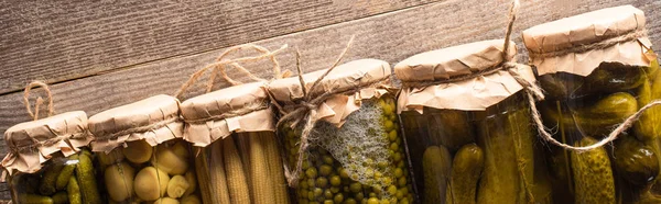 Top view of green tasty homemade pickles in jars on wooden rustic table, panoramic shot — Stock Photo