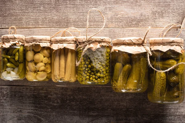 Top view of green tasty homemade pickles in jars on wooden rustic table — Stock Photo