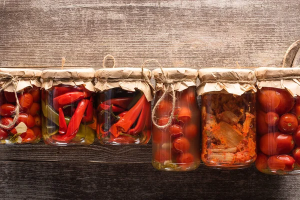 Top view of red homemade tasty pickles in jars on wooden table — Stock Photo