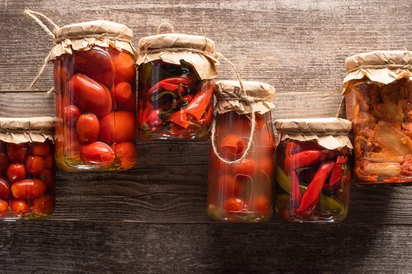 Top view of red homemade tasty pickles in jars on wooden table — Stock Photo