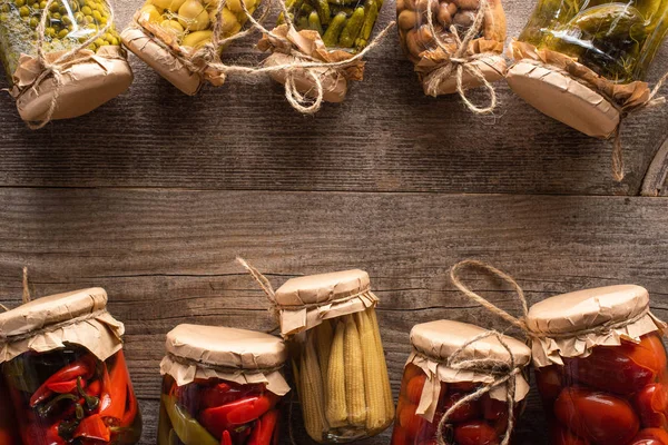 Top view of homemade tasty pickles in jars on wooden table with copy space — Stock Photo