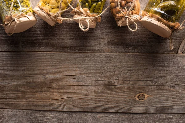 Top view of homemade tasty pickles in jars on wooden table with copy space — Stock Photo