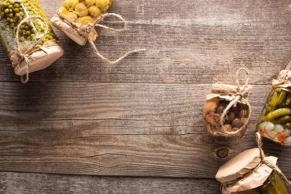 Vue de dessus des cornichons savoureux faits maison dans des bocaux sur une table en bois avec espace de copie — Photo de stock