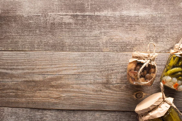 Vue de dessus des cornichons savoureux faits maison dans des bocaux sur une table en bois avec espace de copie — Photo de stock