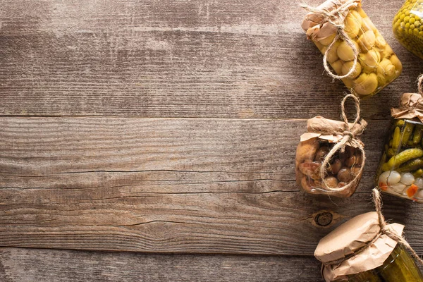 Top view of homemade tasty pickles in jars on wooden table with copy space — Stock Photo