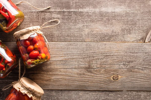 Top view of red homemade tasty pickles in jars on wooden table with copy space — Stock Photo