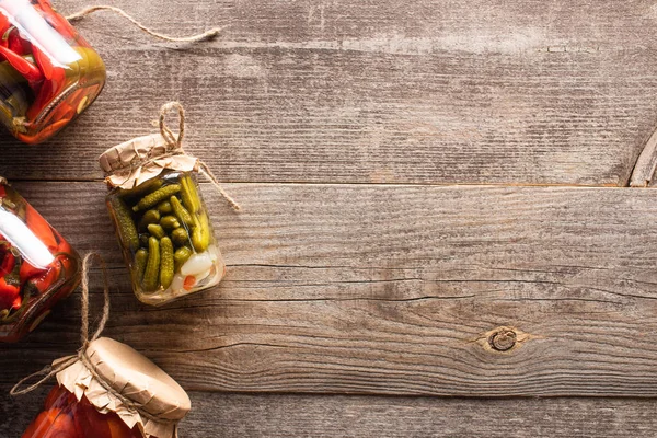 Vue de dessus des cornichons savoureux faits maison dans des bocaux sur une table en bois avec espace de copie — Photo de stock