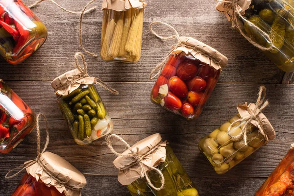 Blick von oben auf frische hausgemachte leckere Essiggurken in Gläsern auf Holztisch — Stockfoto