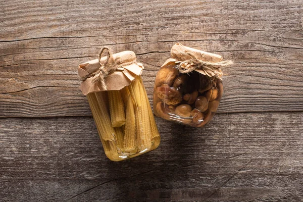 Blick von oben auf köstliche hausgemachte schmackhafte eingelegtes Mais und Pilze auf rustikalen Holztisch — Stockfoto
