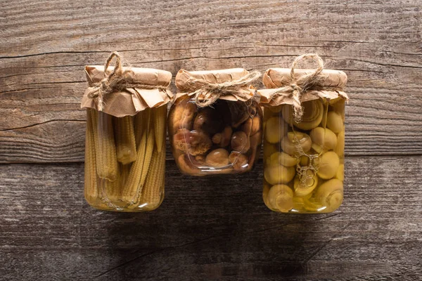 Vista superior de delicioso milho caseiro saboroso em conserva e cogumelos na mesa rústica de madeira — Fotografia de Stock
